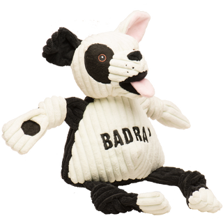 Side view of Jonny Justice durable plush corduroy dog toy: the dog has white and black fur, white left ear, black right ear, black right outer-eye, with brown eyes, white pupils, a plush-out black nose, and mouth. has a black and white furred right arm, the word "BadRap" across the chest, black furred legs, white paws, and is squeaky with knotted limbs.