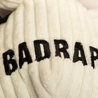 Close up image of the word "BadRap" written on dog shaped durable plush corduroy dog toy chest to show embroidery detail.