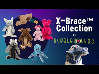 Promotional video for the HuggleHounds® X-Brace™ collection, showing durable plush dog toys with reinforced design. Scenes include close-ups of toy materials, stitching, dogs playing with the toys, and packaging. The video emphasizes toughness inside and softness outside, with product branding visible