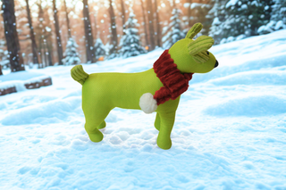 Green dog toy with a red scarf in the snow