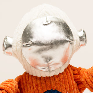 Metallic helmet with a face design worn by a person in an orange sweater on a light background