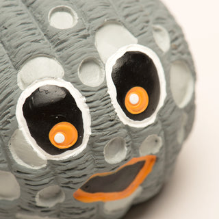 Close-up of a textured object resembling a creature with large eyes and an open mouth.