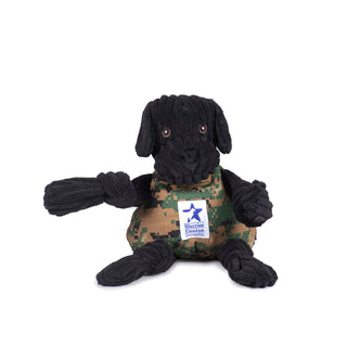 Black lab durable plush corduroy dog toy: black furred head and limbs, with brown open eyes and floppy ears. Camo body, with white Warrior Canine Connection logo in the middle, and is squeaky. 