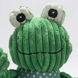 Close up image of frog shaped durable plush dog toys: has green skin, white outer-eyes, black eyes, white pupils, and has a friendly smile. 