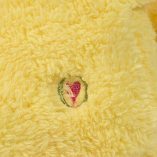 Close up view of HuggleGroup logo on golden-yellow furred, dog shaped, plush dog toy. 