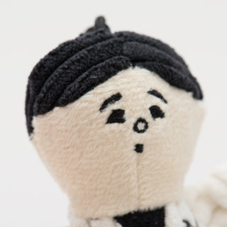 Close up of tiny plush corduroy dog toy veterinarian face with black hair.