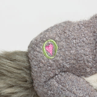 Close up image of HuggleGroups logo on the right side of the gray Squirrel plush dog toy.