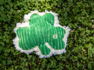 Green corduroy plush shamrock dog toy with fluffy HuggleFleece® fabric on the back and squeaker inside sitting in clover grass.