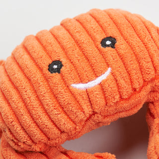 Close up view of orange crab's smiling face showing corduroy texture and embroidered face details.