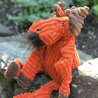 Side view of orange moose durable plush corduroy dog toys in large and small with knotted limbs, brown antlers, inner ears, and hooves, hairy brown beard tuft, and black embroidered eyes and nostrils sitting on rock.