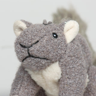 Close up image of plush dog toy shaped like a squirrel with gray fur to show texture of fabric and embroidery detail.